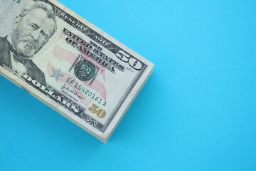 Big amount of fifty dollar bills in thick stack lies on bright blue color paper background