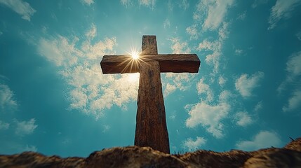 Wall Mural - A wooden cross against a bright blue sky with clouds and sun rays, perfect for Christian-themed banners