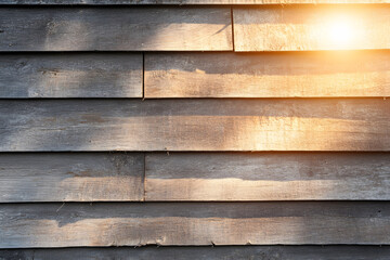 A close-up of weathered wooden planks with warm sunlight reflecting, showcasing a rustic texture and natural beauty