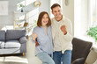 © Studio Romantic - Positive married couple celebrating success together with happiness and teamwork at home living room. Strong family relationship is marked by togetherness, joy, and shared achievements.