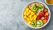 © OngCaLucK - A vibrant bowl of fresh fruits including mango, kiwi, and strawberries, alongside a slice of bread topped with mint, perfect for a healthy breakfast.
