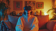 © Olena - A young adult sitting on a couch, immersed in a virtual world using a VR headset, surrounded by modern furnishings in a cozy living room setting