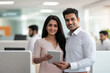© PRASANNAPIX - Indian man and woman in an office, holding a tablet and smiling
