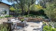 © hana - Outdoor Patio with Stone Walls and Woven Furniture surrounded by Lush Greenery