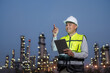 © PhugunStock - Asian male engineer standing and inspecting work with his finger pointing Wearing a safety uniform, standing in front of an oil refinery with a tablet device monitoring the operations of the refinery.