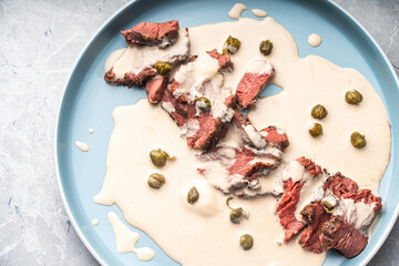 Wall Mural - Vitello tonnato a traditional Italian dish of meat with tuna and anchovy cream sauce. Thin slices of beef in vitello tonnato sauce.Top view, close-up. High quality photo