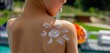 © Anna - smiling boy wearing glasses and sunscreen with a sun painted on his shoulder. sun protection
