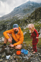 Wall Mural - father and child on picnic in mountains camping - family travel parent and daughter cooking using ga