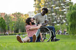 © Lomb - Friends with prosthetic leg and wheelchair support each other. Diversity and human connection bonding in urban park