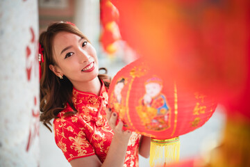 A woman in a red Chinese dress holding a red lantern. The lantern has a picture of a man and a woman on it