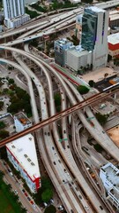 Wall Mural - Cars move by the multiple freeways in the metropolis downtown. Cityscape of Miami, Florida, USA from top. Vertical video