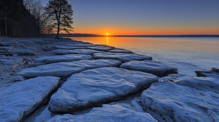 Canvas Print - Sunrise over calm lake with rocky shoreline.