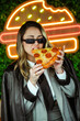© dolores - Joven empresaria comiendo pizza frente a luces de neón en la calle