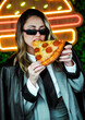 © dolores - Joven empresaria comiendo pizza frente a luces de neón en la calle