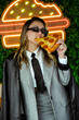 © dolores - Joven empresaria comiendo pizza frente a luces de neón en la calle