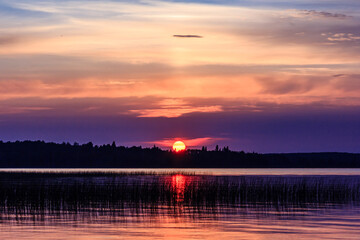 Wall Mural - a sunset over a lake with a large sun in the sky