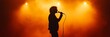 © olga_demina - Silhouette of a singer holding a microphone and performing live on a stage filled with orange backlight and smoke, creating a dramatic and atmospheric scene