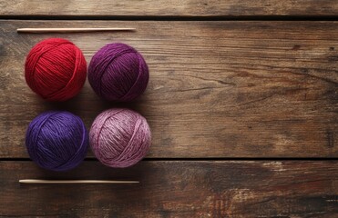 Yarn balls in assorted colors and knitting needles placed on a rough wooden surface