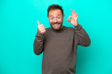 Wall Mural - Middle age caucasian man isolated on blue background showing ok sign and thumb up gesture