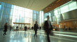 © Easy - Business people in formal attire rush by in a sleek office lobby, showcasing a dynamic atmosphere filled with glass and sunlight during the day.
