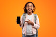 © Prostock-studio - School And Technology. Excited Black Girl Pointing At Phone Blank Screen Showing Smartphone To Camera Recommending Application, Wearing Backpack Isolated Over Yellow Studio Background, Mockup