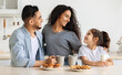 © Prostock-studio - Cute happy arab family having breakfast while spending weekend together at home, cheerful young father, mother and curly little girl sitting at kitchen, drinking coffee and milk with homemade cookies