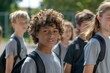 © Iigo - Portrait of a cute mixed race boy with curly hair looking at camera while standing in front of his classmates