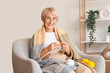 © Pixel-Shot - Old woman with blanket knitting in armchair at home
