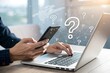 © mdbhraju76 - image features a close-up of hands operating a smartphone and laptop on a desktop, with a blurred abstract question mark interface in background