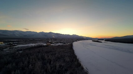 Wall Mural - Captivating view of a sunset illuminating snow-covered mountains and a frozen river in a tranquil setting. Nature's beauty is on full display in this remote landscape.