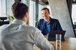 © Westend61 - Smiling businessman taking interview of candidate at desk in office