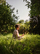 © Westend61 - Woman holding flower and sitting on grass in public park