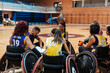 © Westend61 - Coach sitting near team members and explaining at sports center