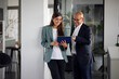 © Westend61 - Businessman and woman holding tablet PC near wall at office