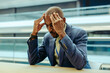 © Jacob Lund - Frustrated businessman holding head in modern office setting