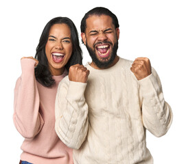 Wall Mural - Young Latino couple in studio cheering carefree and excited. Victory concept.