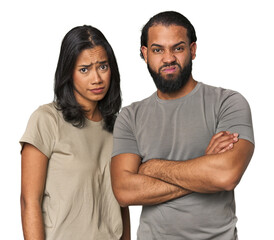 Wall Mural - Young Latino couple in studio unhappy looking in camera with sarcastic expression.