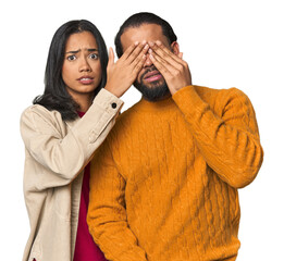 Wall Mural - Young Latino couple in studio afraid covering eyes with hands.