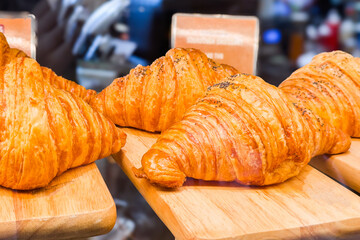 Freshly baked croissants in the pastry display of a bustling bakery shop. Golden, crispy crust delicious French bread is the gourmet treat for breakfast or a tasty snack with aroma of puff pastry.