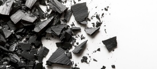 Poster - Black Charcoal Fragments Arranged on White Background with Ample Copyspace for Text and Creative Design Elements