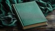 © AImmersive Imagery - Antique green fabric covered book resting on textured wooden surface with soft draped fabric background