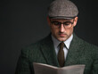 © photobuay - man wearing tweed suit and flat cap reads document with focused expression