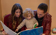 © Connect Images - Parents and their young child are engaged in reading a large picture book together, with focus and enjoyment evident in their interaction. Cleveland, Ohio, USA