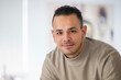 © Connect Images - Smiling man with short curly hair wearing a beige shirt against a blurry background, Netherlands