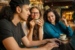© Connect Images - Three friends enjoying coffee and laptop time at a cozy indoor café, Berlin, Germany
