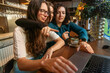 © Connect Images - Three women enjoy a conversation and coffee at a cafe table, one engaging with a laptop, Berlin, Germany