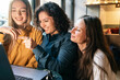© Connect Images - Three colleagues collaborate on a project using a laptop at a sunlit cafe, Berlin, Germany