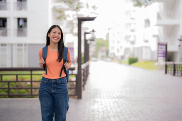 Young asian student smiling and walking in the university campus, carrying a backpack and wearing casual clothes, enjoying her education journey