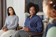 © Seventyfour - Portrait of Black woman as female therapist working with group of teenagers in school counseling session copy space
