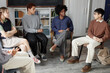 © Seventyfour - High angle view of African American adult woman as female therapist talking to teenage children sitting on chairs in circle during support group meeting